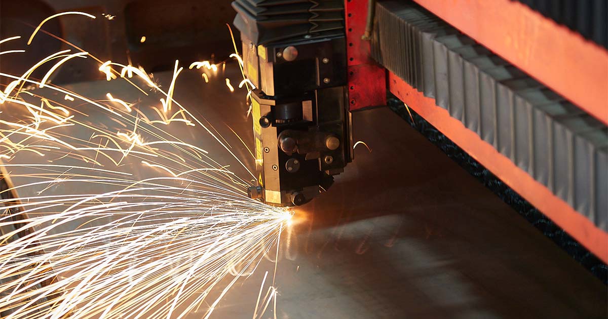 CNC laser cutting machine creating precision cuts in a metal sheet, producing bright sparks.